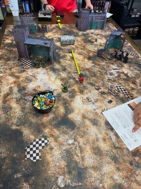 Miniature armies and terrain on an Apocalypse Games battlefield